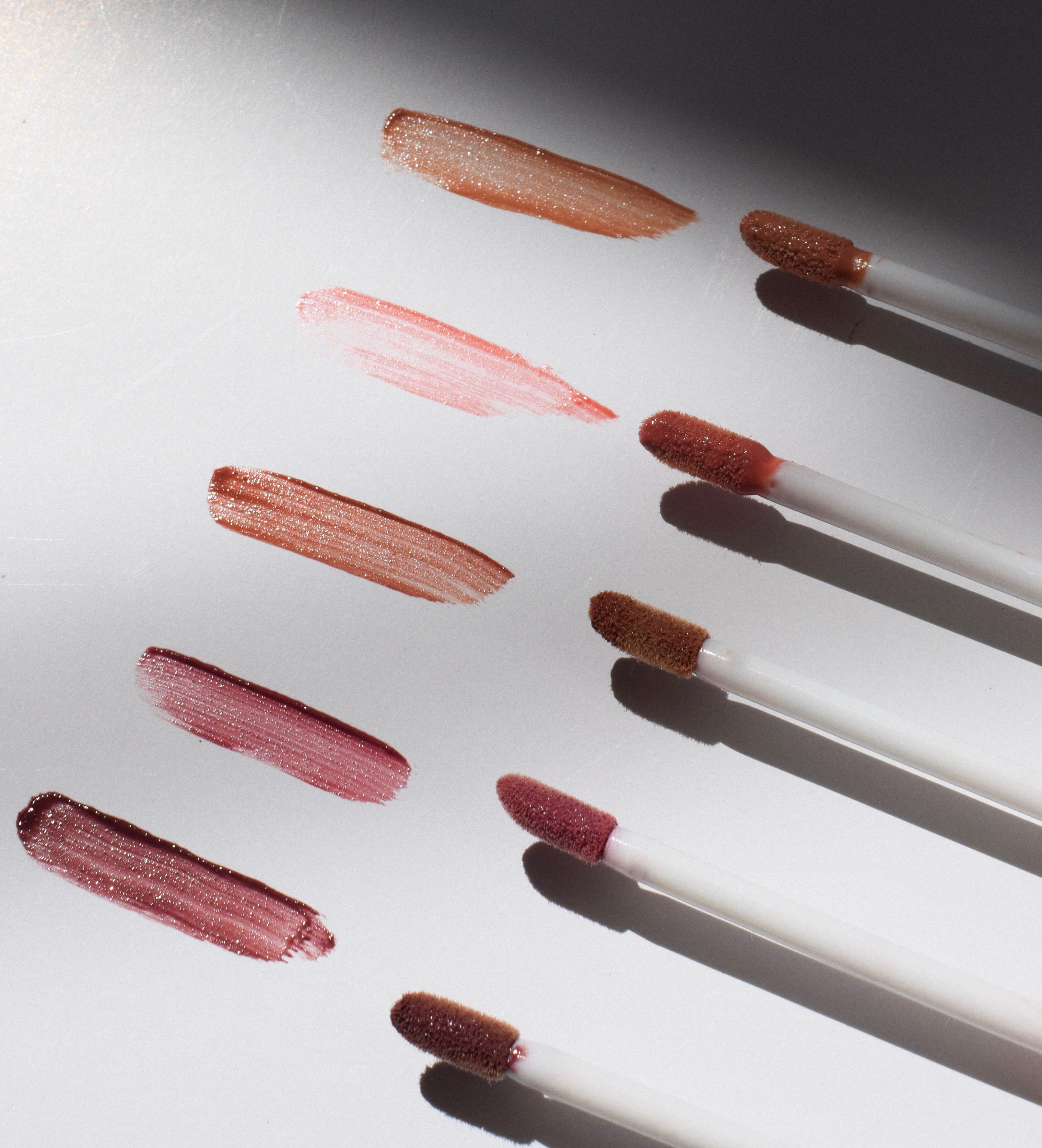 Lipstick applicators with swatches of red and pink lipstick on a white background