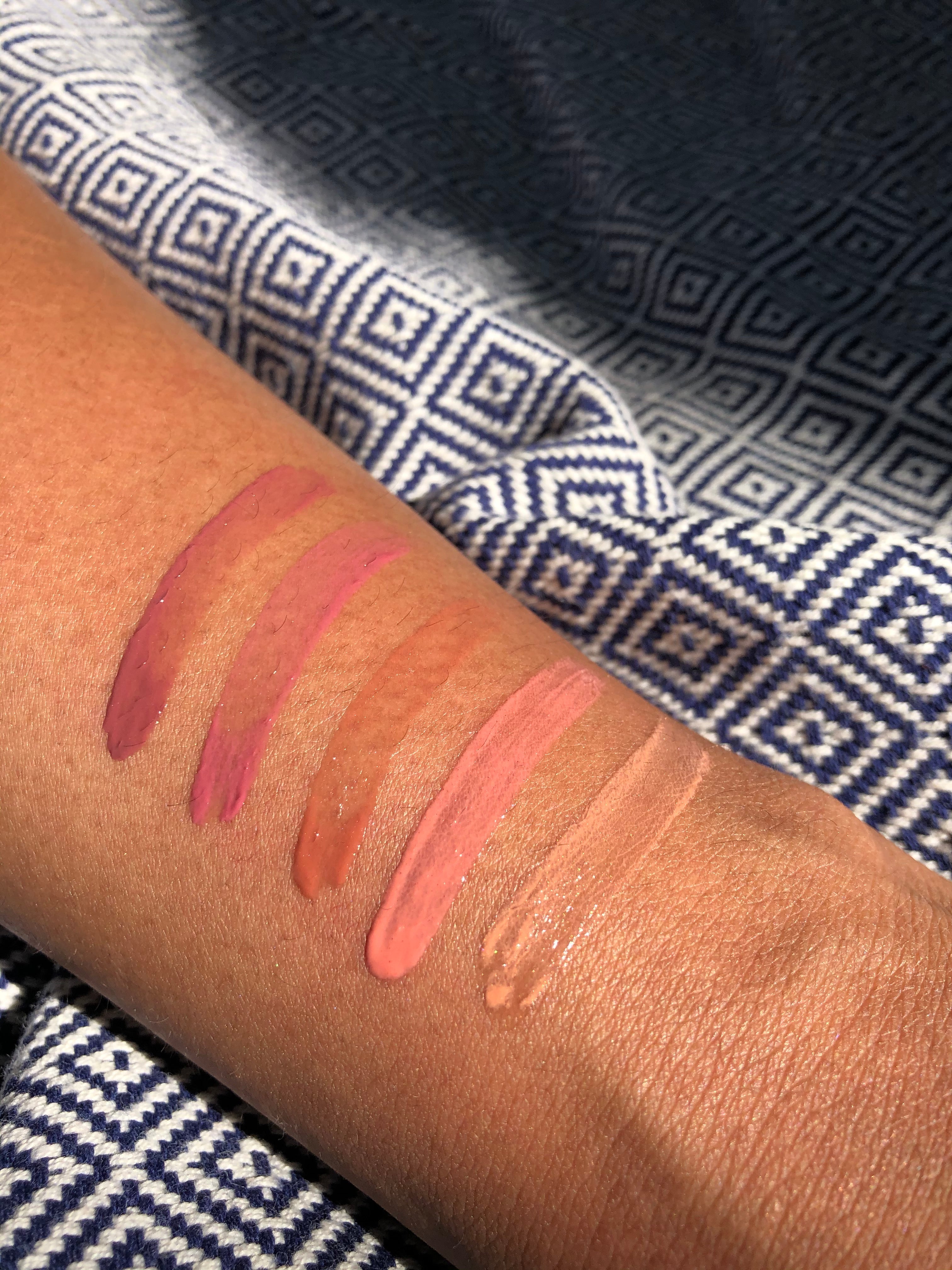 Lipstick swatches on a person's arm with a patterned fabric background