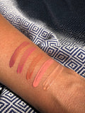 Lipstick swatches on a person's arm with a patterned fabric background