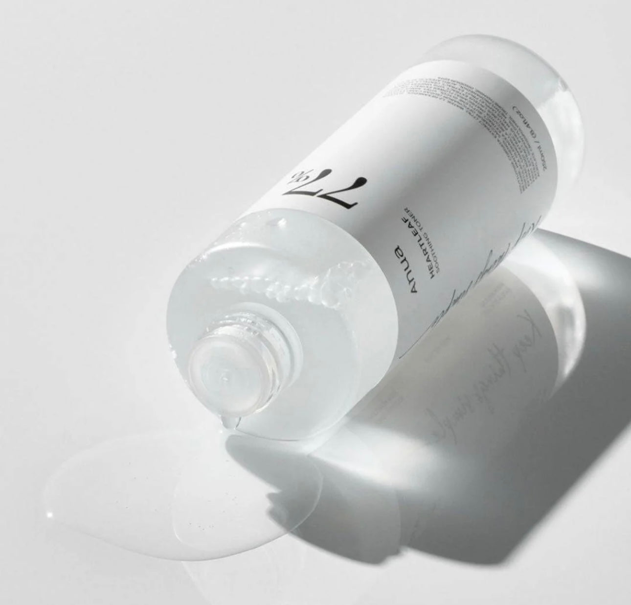 Close-up of the clear, watery texture of the Anua 77 toner being applied to a cotton pad.