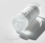 Close-up of the clear, watery texture of the Anua 77 toner being applied to a cotton pad.