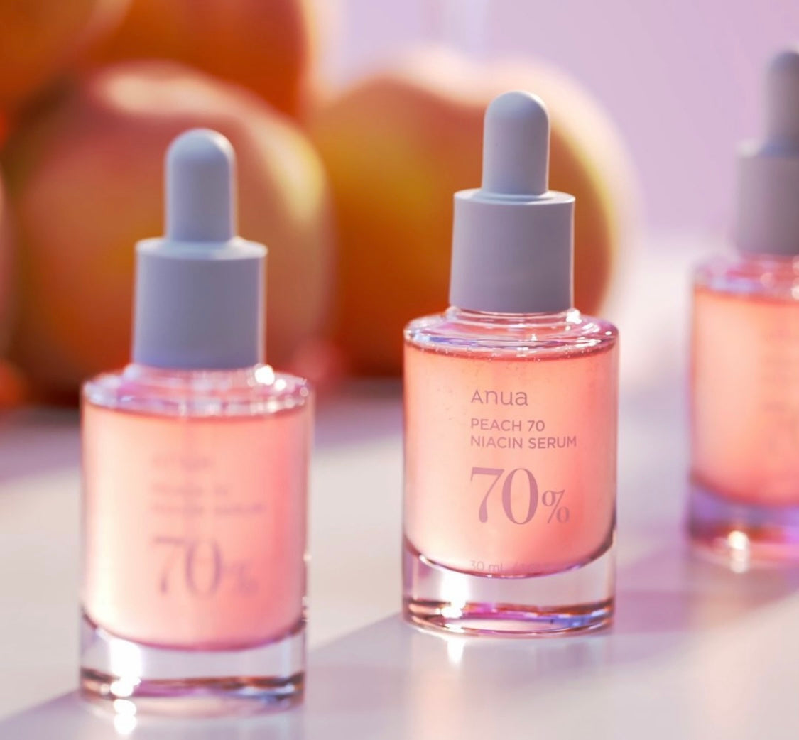 ANUA Peach 70 Niacin Serum bottle placed next to its box with peach extracts visible in the background.