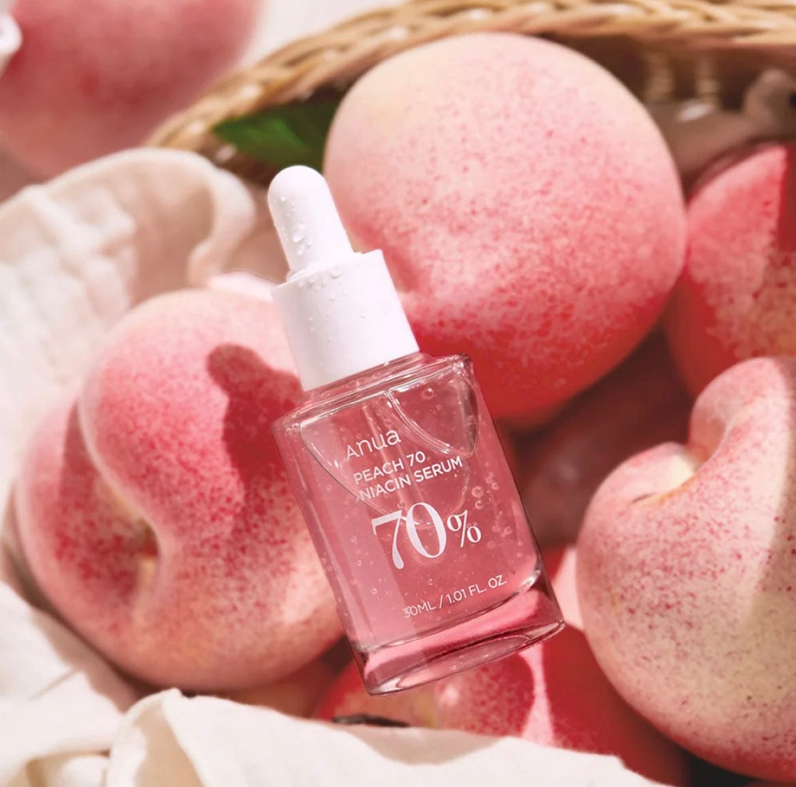 Dropper applying a drop of ANUA peach 70 niacin serum onto a finger for skincare routine.