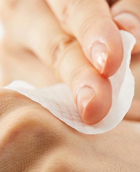 Person gently swiping an original clear pad cosrx on their cheek for a quick skincare step.