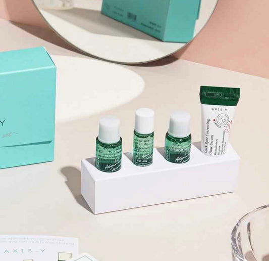 All four Axis Y mini skincare bottles laid out on a table outside the box.