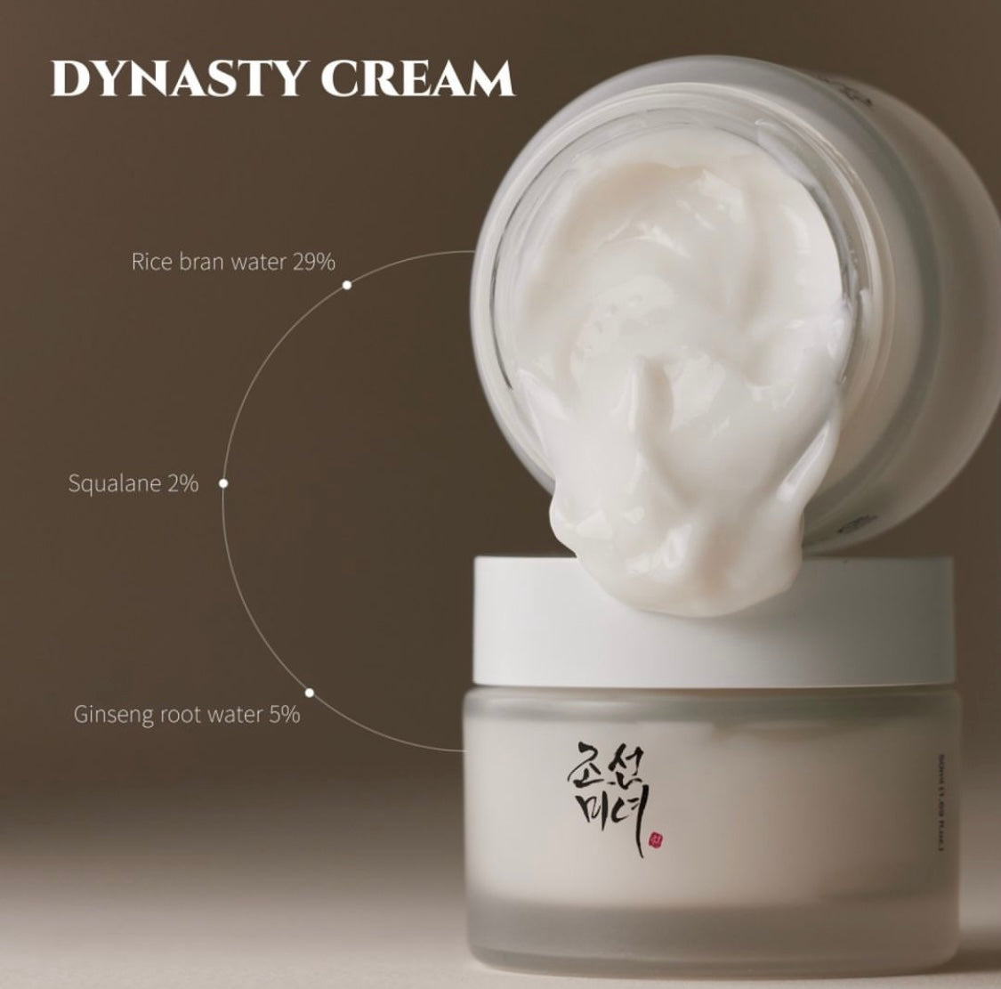 Open jar of Beauty of Joseon Dynasty Cream showing its rich white cream texture. The label on the jar and the spoonful of cream emphasize key ingredients like ginseng and honey.