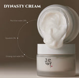 Open jar of Beauty of Joseon Dynasty Cream showing its rich white cream texture. The label on the jar and the spoonful of cream emphasize key ingredients like ginseng and honey.