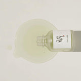 A drop of the Beauty of Joseon calming serum with green tea panthenol being applied to the skin, showing its clear, lightweight texture.