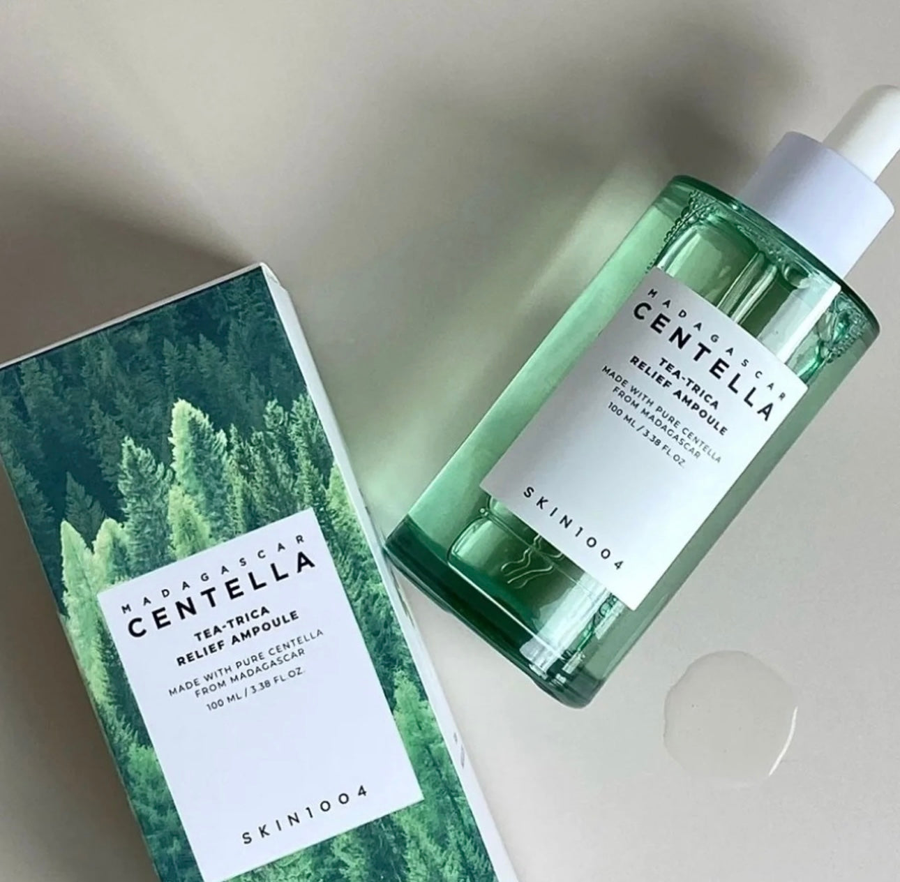 Close up of the SKIN1004 Tea Trica Relief Ampoule dropper dispensing the lightweight serum onto the back of a hand.